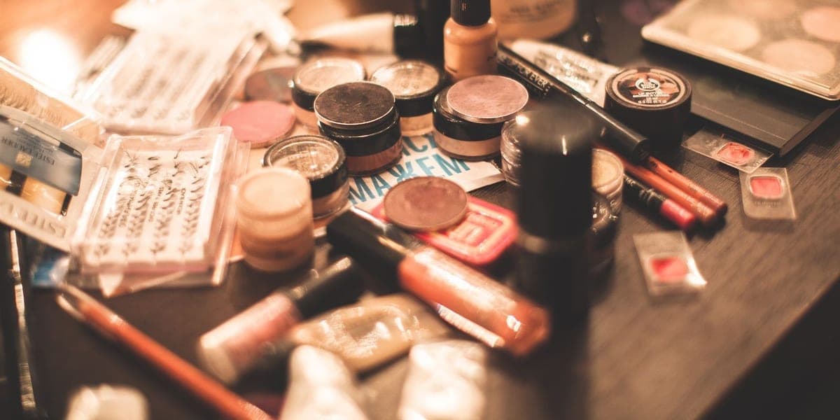 Makeup compacts, palettes and cosmetic bottles spread across a vanity table.