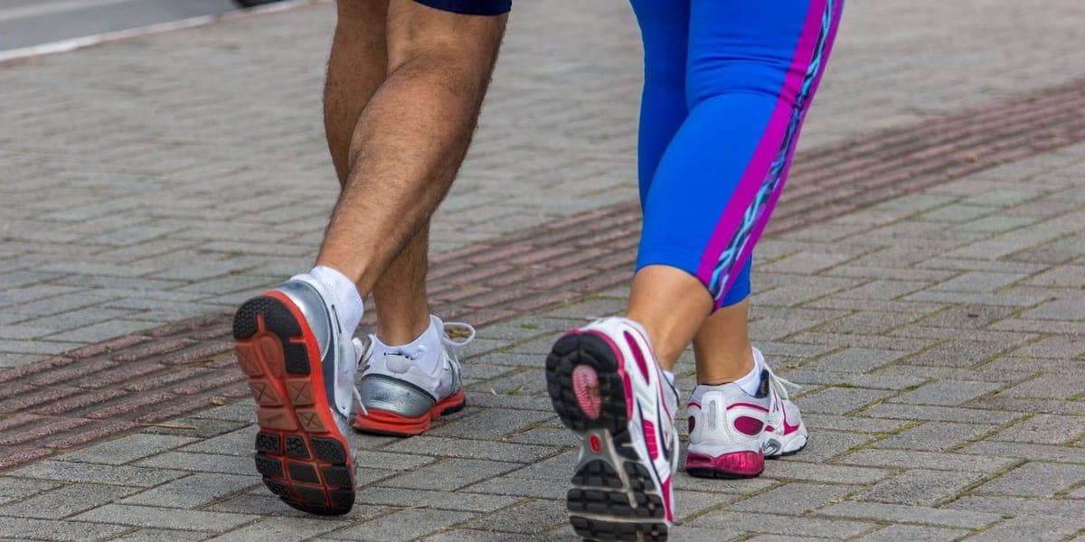 Two people in athletic shoes moving along a paved path
