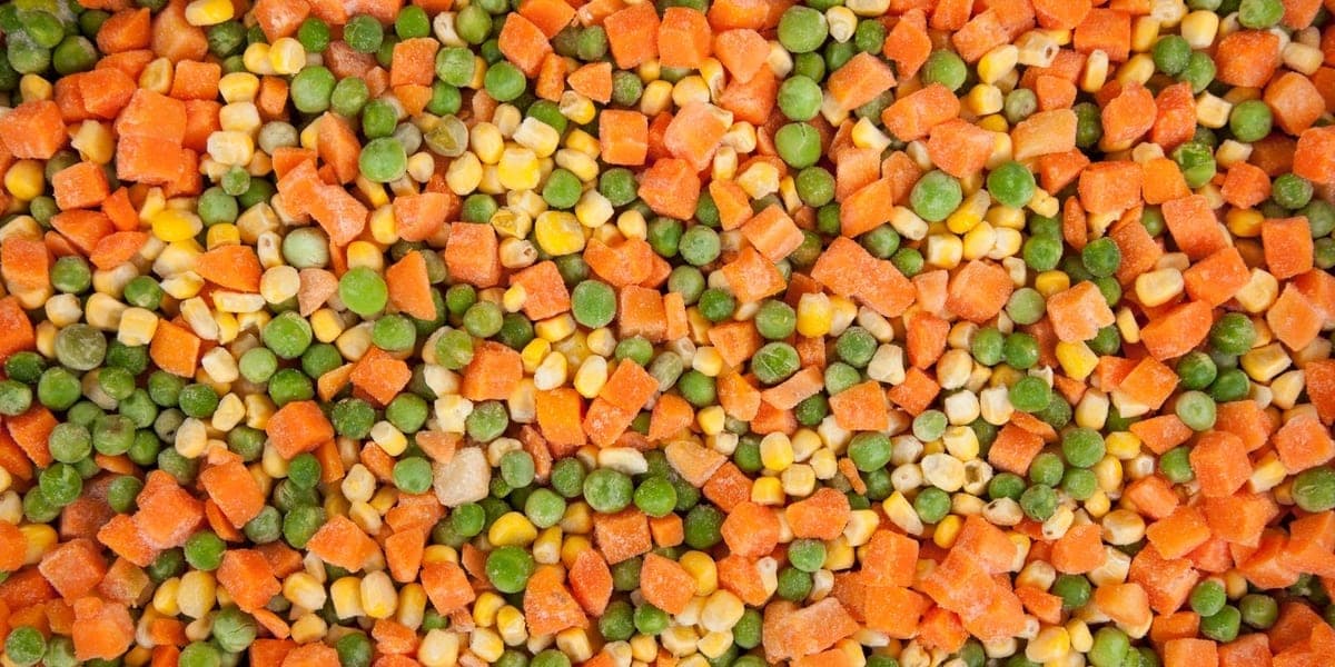 A close-up of frozen peas, corn kernels, and diced carrots.