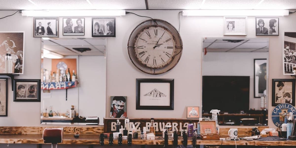 Mirrors, a wall clock and styling products above a salon workstation