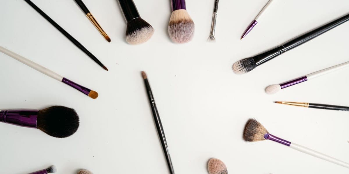 Makeup brushes with black, white and purple handles arranged on a white surface.