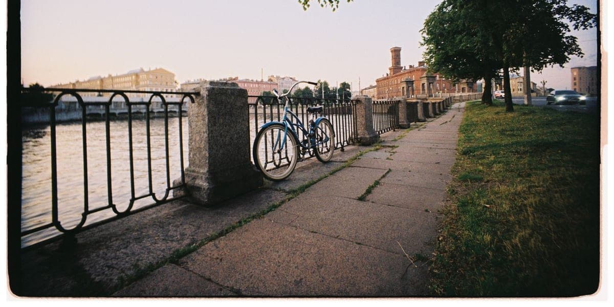 A blue bicycle parked beside railings along a riverside path