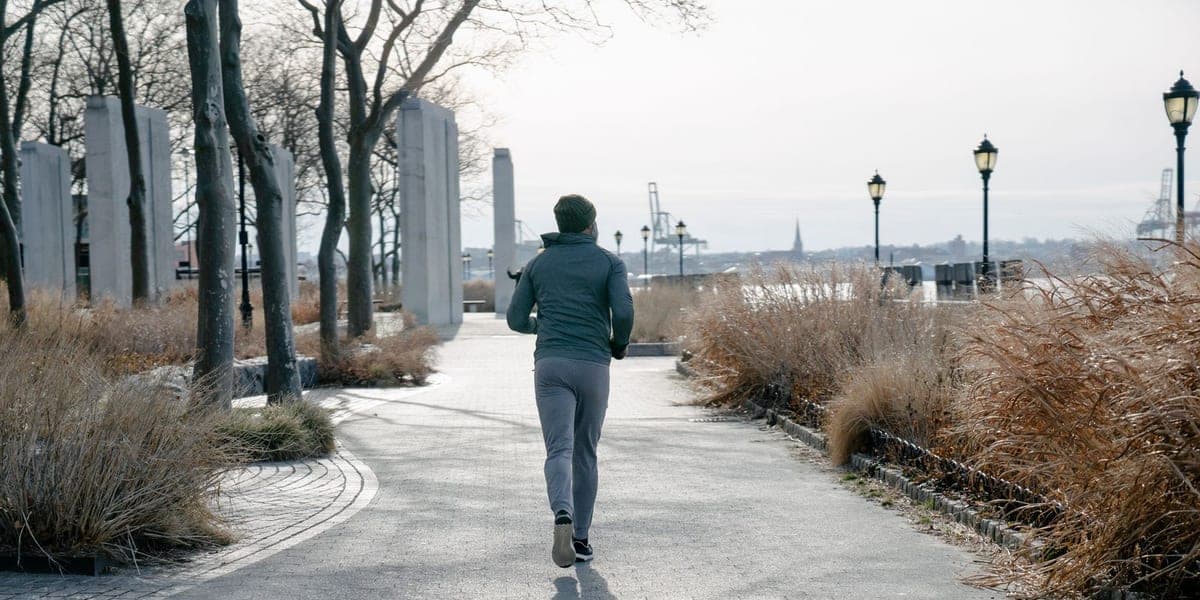 Runner seen from behind on a paved path through a park