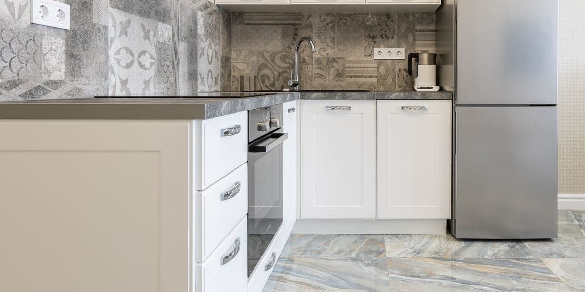 Silver refrigerator beside white cabinets and a kitchen counter